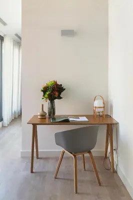 a wooden desk with a chair and a vase of flowers at Casa Mercader - Simaba Group in Barcelona