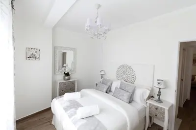 a white bedroom with a white bed and a chandelier at Sitges Centre Mediterranean House- 5 Bedroom, 4 Bathroom, Terrace Courtyard, Private Rooptop Pool in Sitges