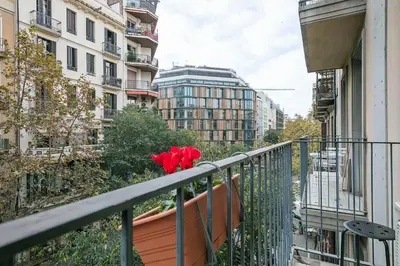 a balcony with red flowers sitting on a railing at Winahost Barcelona Provenza in Barcelona