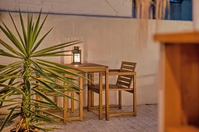 a wooden table and two chairs and a plant at El Niu Apartamentos con terraza Camp Nou in Hospitalet de Llobregat