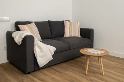 a black couch in a living room with a table at El Niu Apartamentos con terraza Camp Nou in Hospitalet de Llobregat