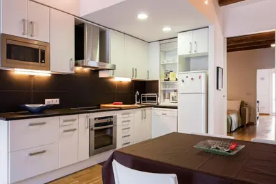 a kitchen with white cabinets and a black and white refrigerator at Moderno y auténtico en el corazón de Poble Sec in Barcelona