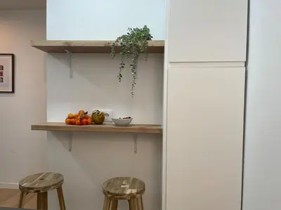 a kitchen with two stools and a shelf with fruit at Jordi home 15 minutes to center by train in Sant Adria de Besos