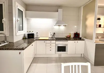 a white kitchen with white cabinets and a sink at Espacioso con patio interior in Sabadell
