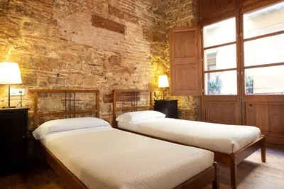 two beds in a room with a stone wall at El Born - Barcelona Center Apartment in Barcelona