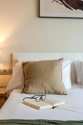a book and glasses sitting on top of a bed at Canela Homes BARCELONA FÒRUM in Sant Adria de Besos