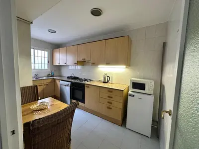 a kitchen with wooden cabinets and a table with a microwave at Relax Holiday Home in Vallromanas