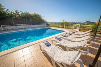a row of lounge chairs next to a swimming pool at Villa Sitges Cambera 10 minutos de Playa andando Muy Comoda Area Tranquila in Sitges