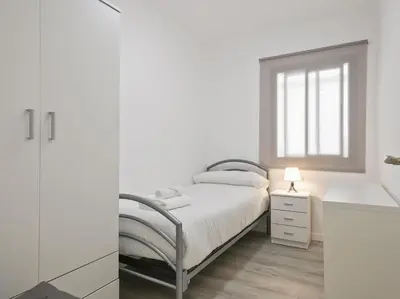 a white bedroom with a bed and a window at Winahost Barcelona Diagonal in Barcelona