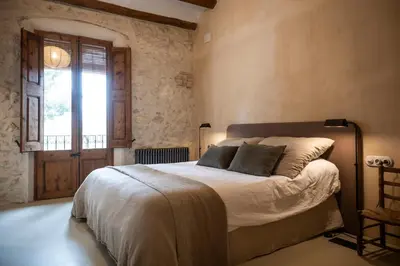a bedroom with a large bed and a window at Mas Grimosach - Masía en finca y bodega ecológica - Adults Only in Sant Pau dʼOrdal