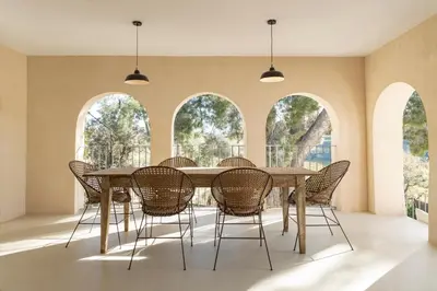a dining room with a table and chairs in front of windows at Mas Grimosach - Masía en finca y bodega ecológica - Adults Only in Sant Pau dʼOrdal