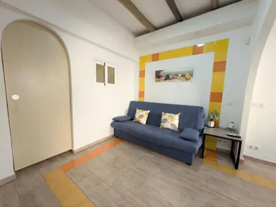 a living room with a blue couch and a table at Zona Camp Nou 15 minutos centro en metro in Hospitalet de Llobregat