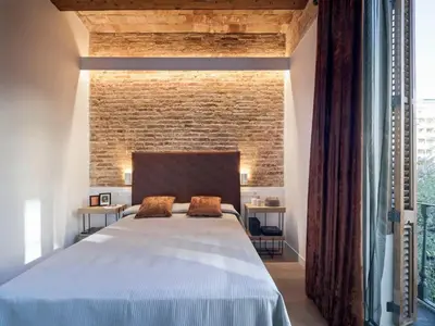 a bedroom with a large bed and a brick wall at Pau Claris - Design apt next to Paseo de Gracia in Barcelona