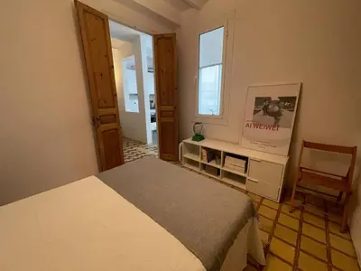 a bedroom with a bed and a chair and a window at Barcelona Besos Apartment | 15' to Plaza Cataluña in Sant Adria de Besos