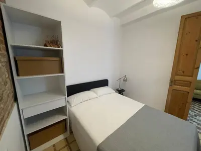 a small bedroom with a white bed and shelves at Barcelona Besos Apartment | 15' to Plaza Cataluña in Sant Adria de Besos