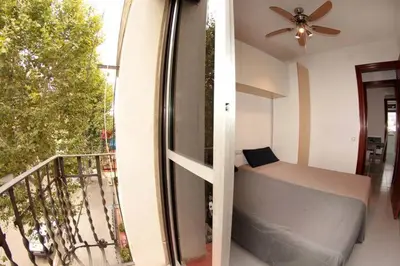 a room with a balcony with a bed and a fan at Modern pad in a great old barrio in Barcelona