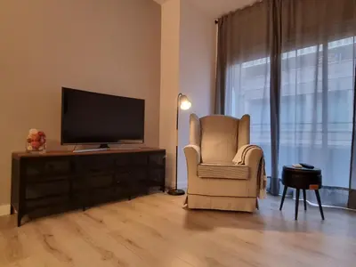 a living room with a chair and a flat screen tv at QEhome - confort, parking y cargador EV en el centro de Manresa in Manresa