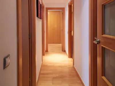 a hallway with a long corridor with two doors at Alcam Cervantes Playa Badalona in Badalona