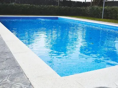 a swimming pool with blue water in a yard at Alcam Cervantes Playa Badalona in Badalona