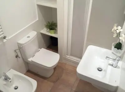 a white bathroom with a toilet and a sink at Sitges Seafront BATLLÓ in Sitges