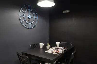 a black table with chairs and a clock on the wall at Spacious 3BRapartment in PobleSec with balcony in Barcelona