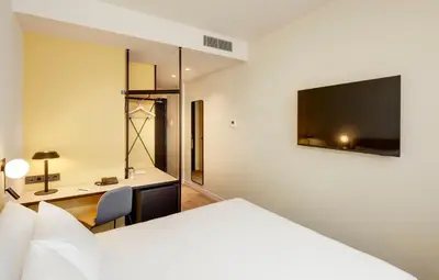 a bedroom with a bed and a desk and a tv at Sercotel Barcelona El Prat in El Prat de Llobregat