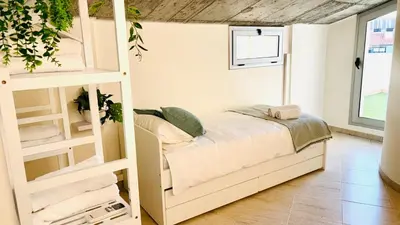 a white bedroom with a bed and a ladder at Dúplex ático familiar by Prestigi in Terrassa