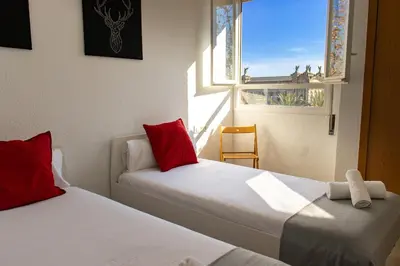 two beds with red pillows in a room with a window at Apartments BCN Central-Colon in Barcelona