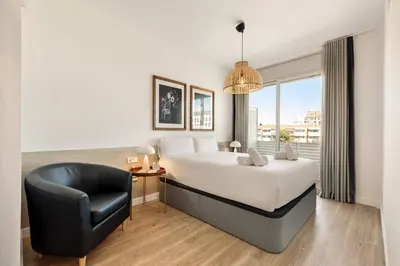 a bedroom with a large bed and a black chair at Ola Living Poblenou Beach in Barcelona