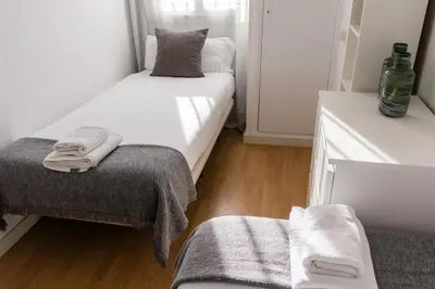 a small bedroom with two beds and a chair at Apartments BCN Central-Drassanes in Barcelona