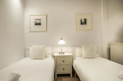 two beds in a room with a lamp on a night stand at E4lle1031 - Studio next to Plaza Espanya in Barcelona
