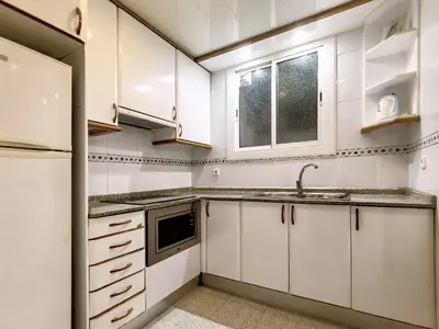a kitchen with white cabinets and a sink and a window at Classbedroom Barcelona Sagrera Apartment in Barcelona