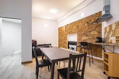 a dining room with a table and chairs and a stone wall at BRAND NEW Pl Espana Sants Fira Apartment 2024 Built, Aplus, AirCon & Heating, Gigabit WiFi, Parking in Barcelona
