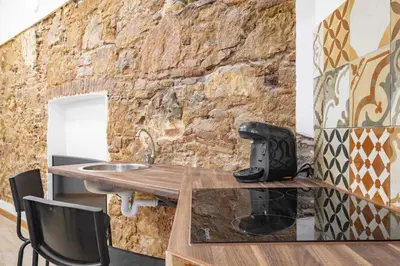 a room with a stone wall and a wooden table at BRAND NEW Pl Espana Sants Fira Apartment 2024 Built, Aplus, AirCon & Heating, Gigabit WiFi, Parking in Barcelona