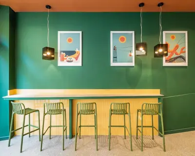 a bar with four stools against a green wall at BYPILLOW Twenty in Barcelona