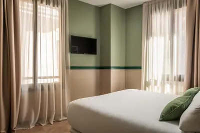 a bedroom with a bed with curtains and a television at BYPILLOW Twenty in Barcelona