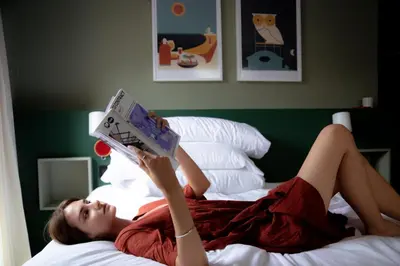 a woman laying on a bed reading a book at BYPILLOW Twenty in Barcelona