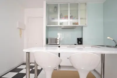 a kitchen with a white counter and two white chairs at Viva Sitges - Mayo Terrace in Sitges