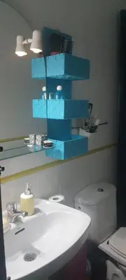 a bathroom with a sink and a toilet with blue shelves at Estudio, privado e independiente in Hospitalet de Llobregat