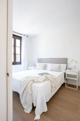 a white bedroom with a large bed and a window at Modern 1 bedroom apartments near Parallel in Barcelona