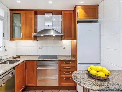 a kitchen with wooden cabinets and a bowl of fruit on a counter at Apartment Eixample Dret Aragó Roger de Lluria by Interhome in Barcelona