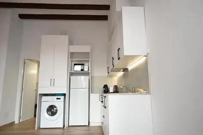 a kitchen with white cabinets and a washer and dryer at Homenfun Dalt Badalona in Badalona