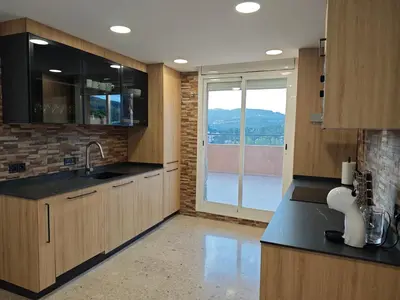 a kitchen with wooden cabinets and a large window at Venecia relax in Vallirana