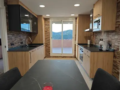 a kitchen with a table and a large window at Venecia relax in Vallirana