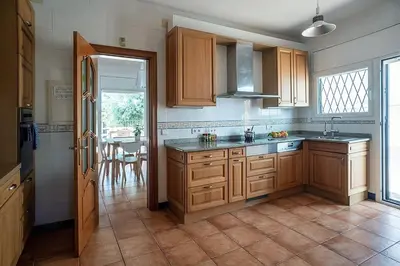 a kitchen with wooden cabinets and a kitchen with a table at Elis house Piscina Privada Villa Mediterránea in Castelldefels