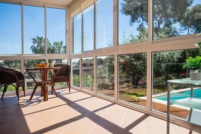 a room with large windows and a table and a pool at Elis house Piscina Privada Villa Mediterránea in Castelldefels