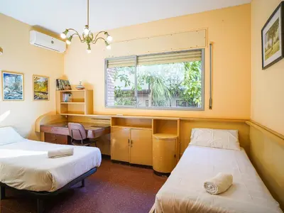 a room with two beds and a desk and a window at Bed BCN Hills House in Barcelona