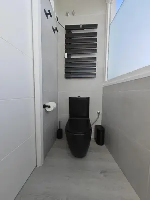 a bathroom with a black toilet in a room at Apartamento con vistas al mar in Viladecáns