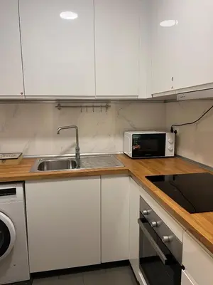 a kitchen with white cabinets and a sink and a microwave at Casa Acogedora in Hospitalet de Llobregat