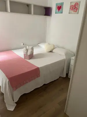 a bedroom with two beds with white walls and wood floors at Alojamiento muy cómodo in Hospitalet de Llobregat